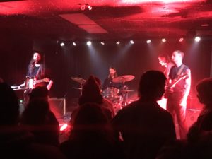 Blessed performing on stage with red lighting.