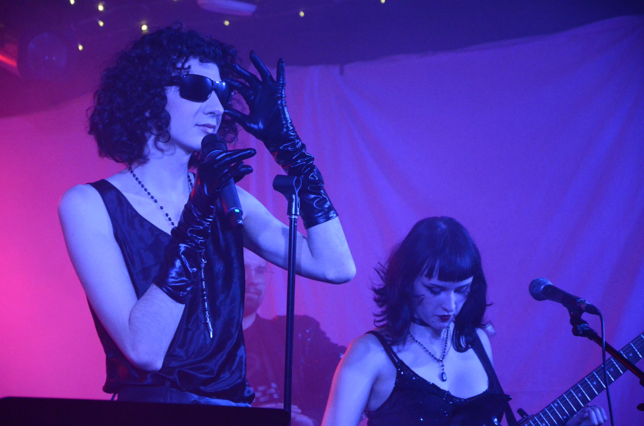 Carlo Capobianco performing on stage. The lighting is pink and purple.
