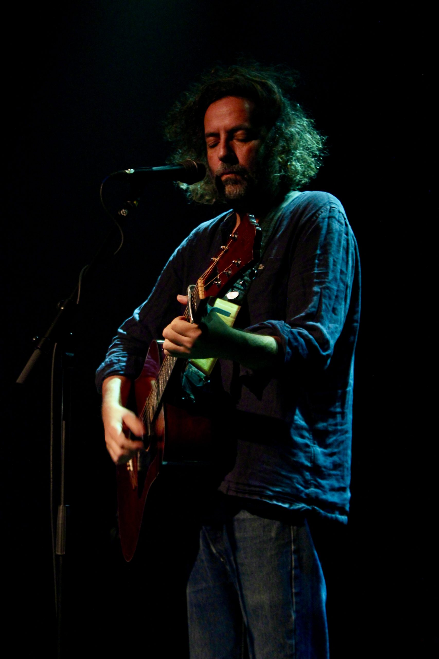 Person standing, playing guitar on stage