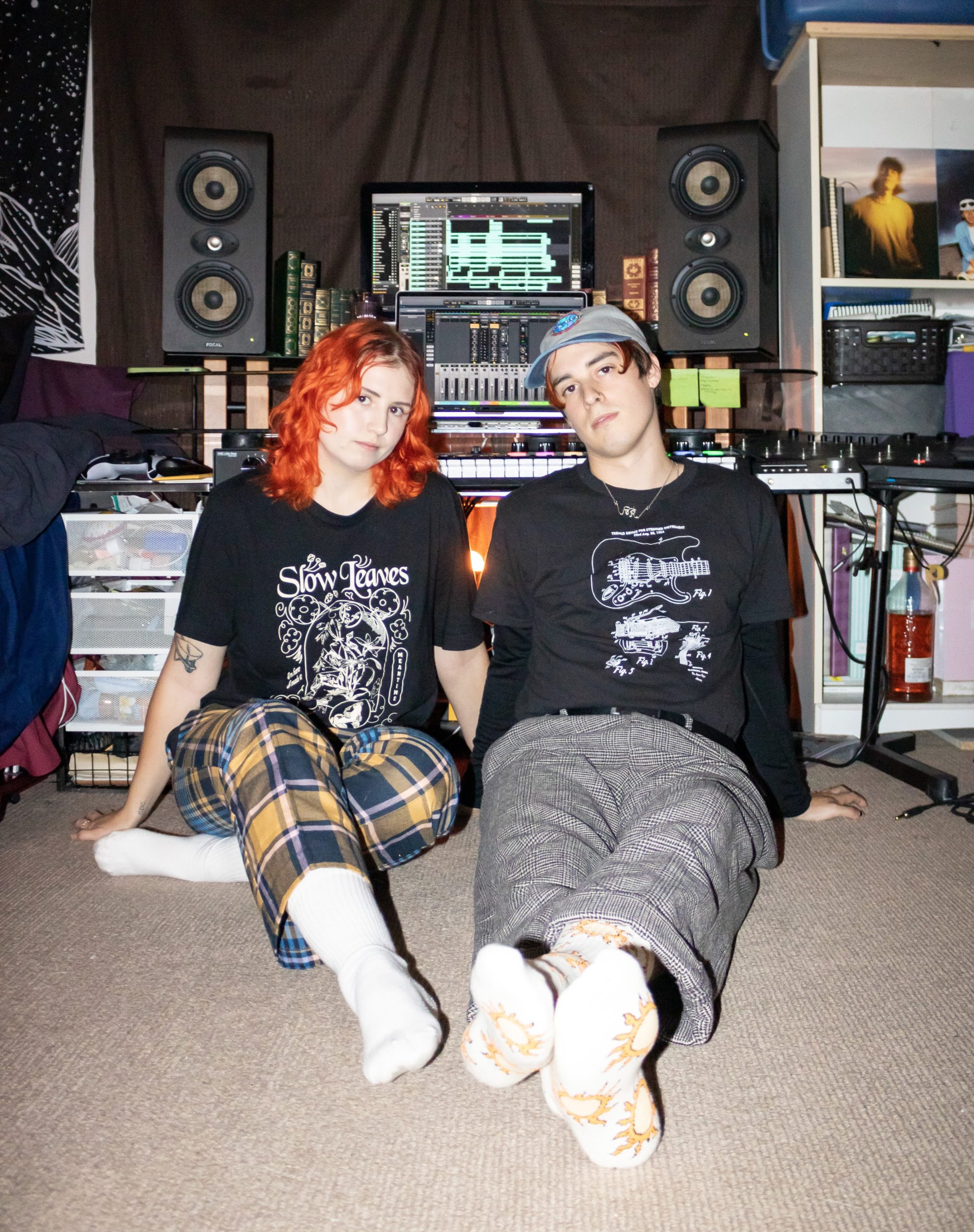 two people sitting on the floor in front of editing equipment and a speaker set-up