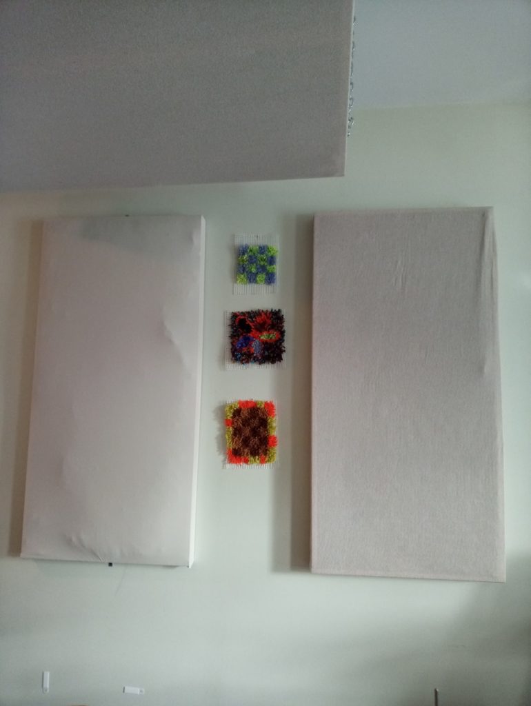 Wall art. Three small fuzzy squares surrounded by two sound panels.