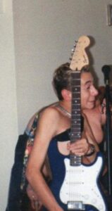 One person in frame facing the side with a guitar in their one hand closest to the camera.