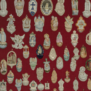 Many religious ornaments and pendants, including angels and crosses, laid out over a red backdrop