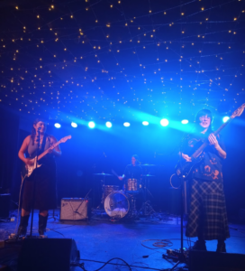 Band members of Veneer performing onstage under blue lights