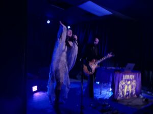 Luana Moth performing onstage. Image is primarily blue tones and dark lit.