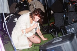 Artist performing on a stage with a microphone.